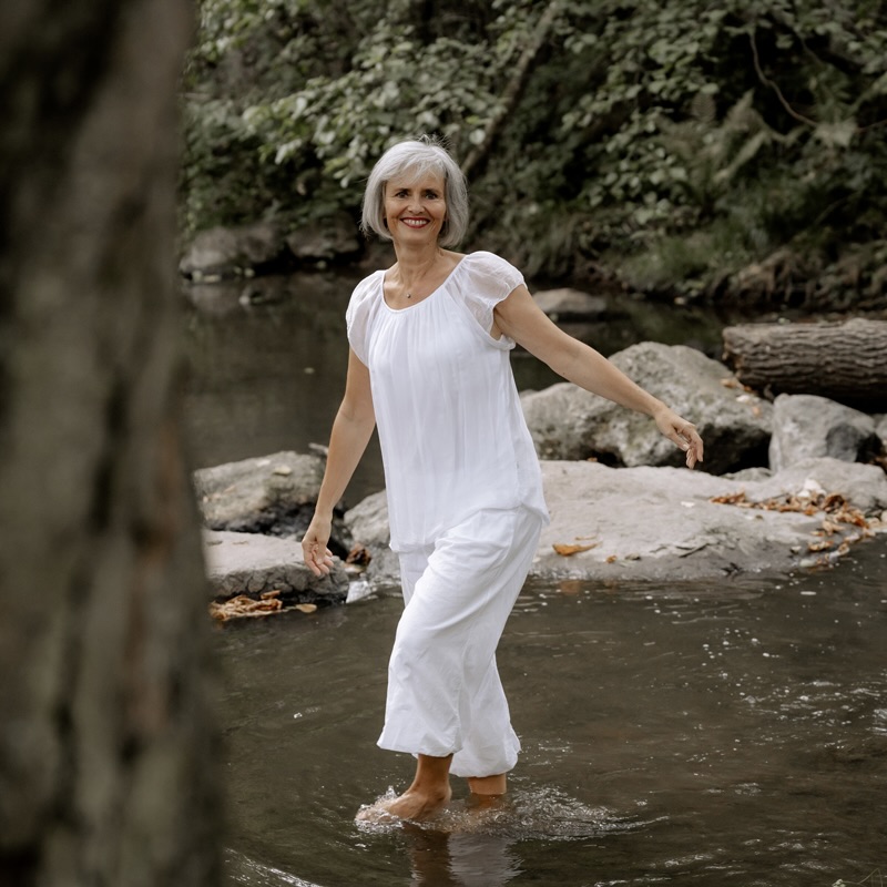 Frau in weiß in Bach laufend